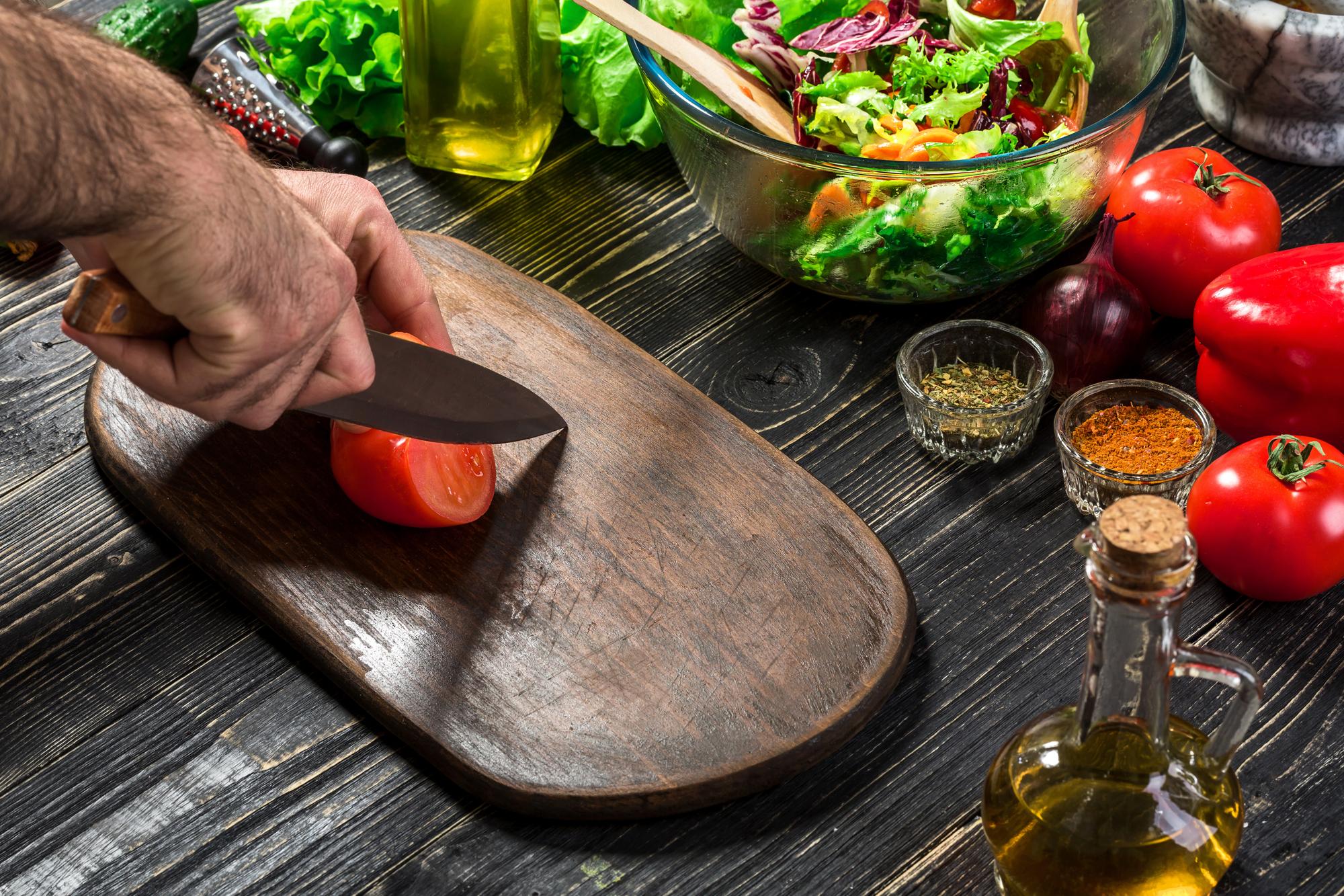 Chef che affetta verdure con cura su tagliere di legno
